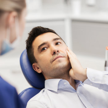 a man is sitting with a toothache in a dental chair
